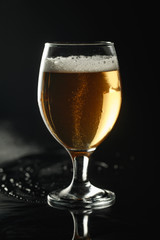 glass of beer with foam on wet surface isolated on black