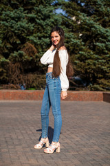 Pretty stylish brunette girl in blue jeans and white blouse