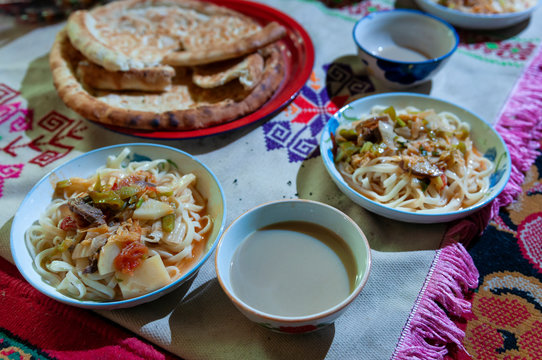 Traditional bowls of noodles on top of rugs on the floor in a Yurt by the Karakul Lake in Xinjiang, China