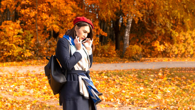 Woman talking by cellphone in the autumn park