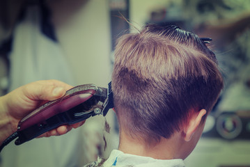 Barber shop. Barber making hairstyle to Caucasian boy using clipper. - 289536901