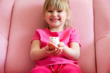 Happy girl holding piggy bank in hands.