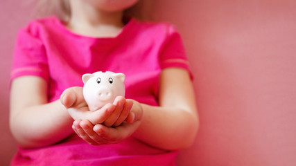 Fototapeta na wymiar Pink piggy bank on children hands.