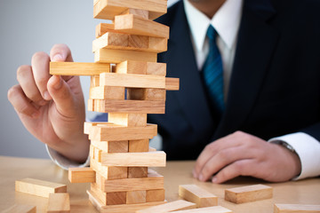 Business travelers are planning and strategy of risk management in business, business and project engineers on the Tower of wooden blocks gambling.