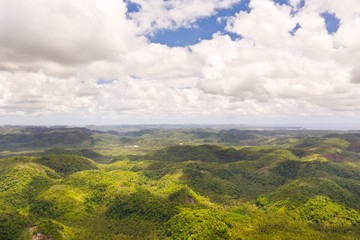 Hills with rainforest, aerial view. Tropical landscape with the jungle. Tropical climate, nature of the Philippines. Hilly terrain and sky with big clouds.