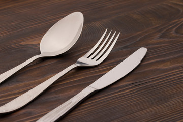 Cutlery Set. Spoon, Fork, Knife on a dark wood background. close up 