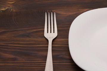 fork and plate on a wood table, close up
