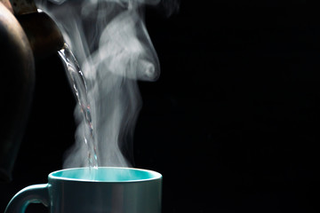 The steam from a cup of coffee or tea on the old wood table and black background, Warm drinks make good healthy, Selective focus.
