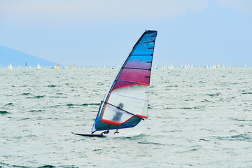 Windsurfing on Lake Garda. Unidentifiable Windsurfer Surfing The Wind On Waves, Recreational Water Sports, Selective focus