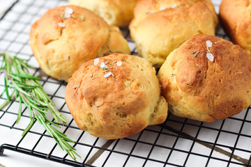 homemade fresh herb bread rolls of Provencal herbs with salt and a sprig branch of rosemary. Bread rolls bakery style on the cooling wrack