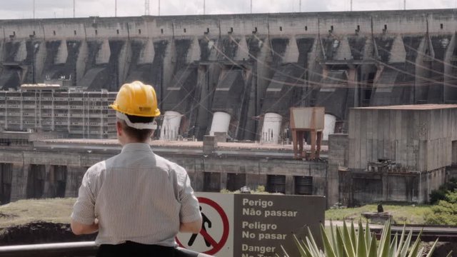 Engineer wearing a safety helmet, supervising the biggest world's dam, Itaipu dam between the border of Paraguay and Brazil. 4k