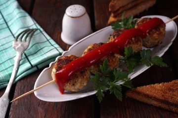 skewered meatballs with tomato sauce and parsley on a plate