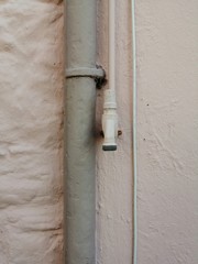 Pink wall with guttering and tap