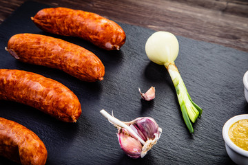 Raw sausages and ingredients on cutting board