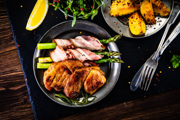 Grilled beefsteak with asparagus and baked potatoes on wooden background