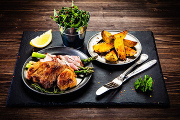 Grilled beefsteak with asparagus and baked potatoes on wooden background