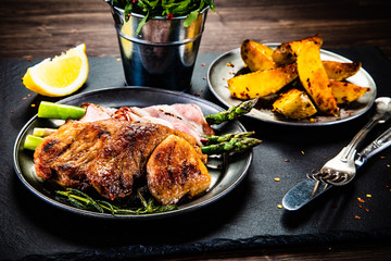 Grilled beefsteak with asparagus and baked potatoes on wooden background