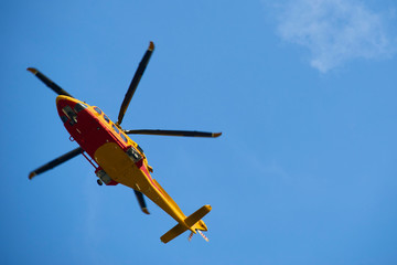 Rescue helicopter moving in blue sky with blur propeller. View from bellow