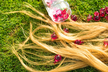 Blond hair nourishment. pink vitamin serum capsule on grass background.Hair loss treatment