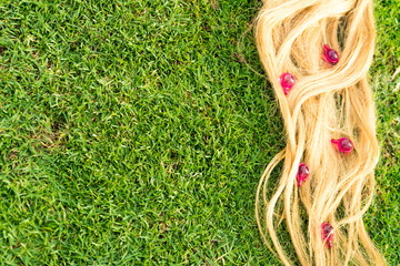 Blond hair nourishment. pink vitamin serum capsule on grass background.Hair loss treatment
