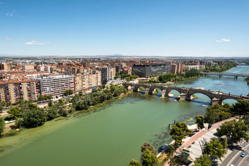 Fototapeta na wymiar Zaragoza city in Spain. Aerial cityscape view over Ebro river with stone bridge .