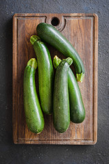 Freshly harvested zucchini, green vegetables on dark background.