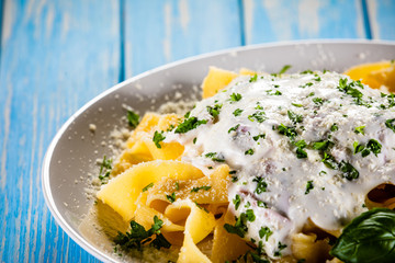 Tagliatelle with cream sauce and herbs on wooden table