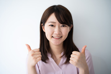 Young business woman showing thumb up gesture against white background