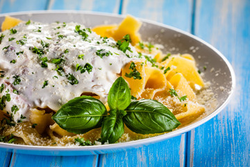 Tagliatelle with cream sauce and herbs on wooden table