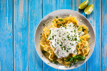 Tagliatelle with cream sauce and herbs on wooden table