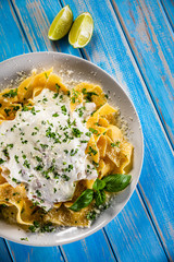Tagliatelle with cream sauce and herbs on wooden table