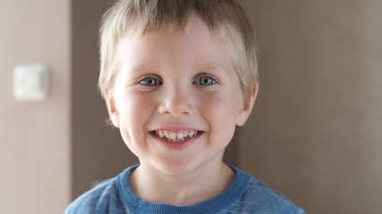 Adorable happy kid baby boy is looking to the camera. Baby looks around and then smiles and laughs. 4 year old fair-haired child with blue eyes smiles at home. Slow motion - Powered by Adobe