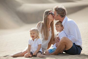 happy family at the beach. Laughing kids. Husband and wife kiss