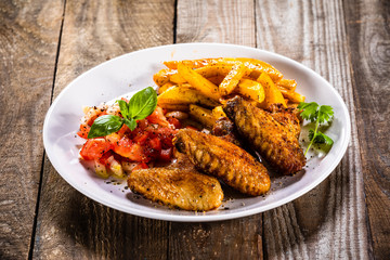 Grilled chicken wings, chips and vegetables