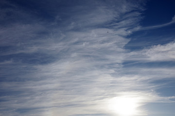 View west of a vivid cloud formation in a summer evening sky at sundown with a distant single airplane high above