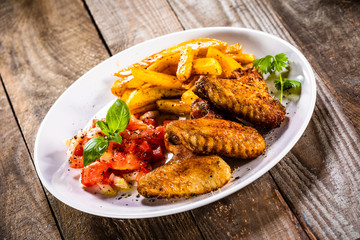 Grilled chicken wings, chips and vegetables