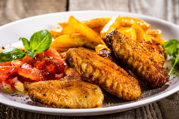 Grilled chicken wings, chips and vegetables