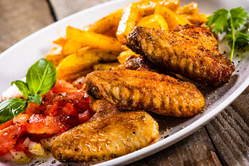 Grilled chicken wings, chips and vegetables