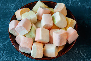 Aerial colorful marshmallow close-up. lies in pottery, plate. Marshmallow on dark grey retro background.  photo dessert with a place to copy space