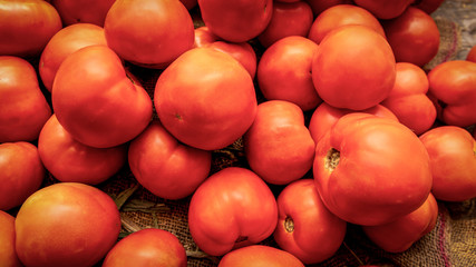 A close-up of ripe, red tomatoes at a fruit and vegetable stand