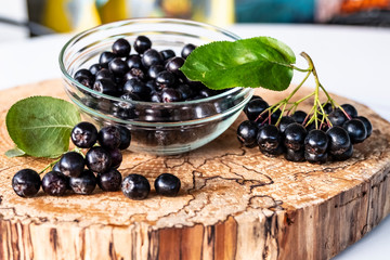 Aronia berries on a wooden background, cut logs. Vitamins and health.