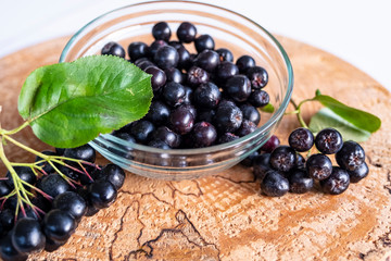 Aronia berries on a wooden background, cut logs. Vitamins and health.
