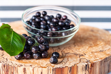 Aronia berries on a wooden background, cut logs. Vitamins and health.