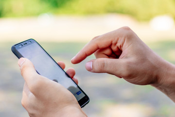 young man holds a phone in his hands on a green background close online shopping or writes a message