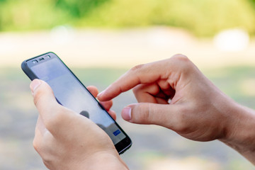 young man holds a phone in his hands on a green background close online shopping or writes a message