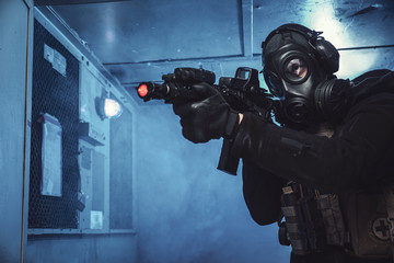 Special unit soldier with gas mask is going out of industrial elevator and aiming a target