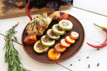 plate with food on the table, grilled vegetables and chicken leg.