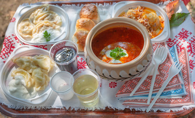 Traditional Ukrainian food borscht and dumplings on a tray covered with embroidered towel