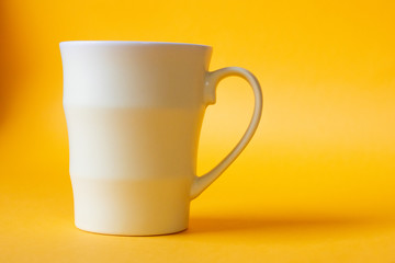 Tender yellow mug close-up on a bright yellow background.