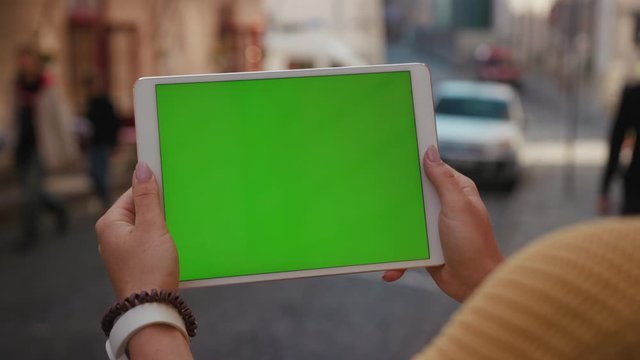 Close up hands woman using tablet device computer with green screen outdoors in street at sunlight horizontal bloom message pad technology chroma key female digital girl app chat finger slow motion